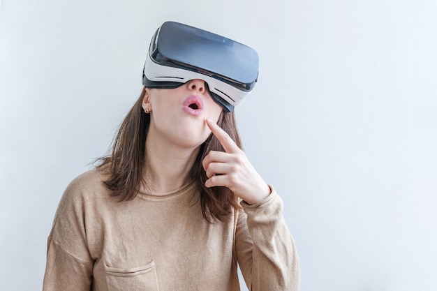 Lächeln Sie junge Frau, die mit VR-Brillenhelm-Headset der virtuellen Realität auf Weiß trägt