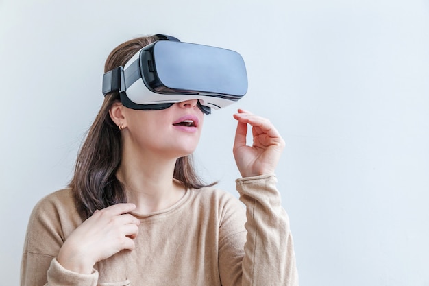 Lächeln Sie junge Frau, die unter Verwendung des VR-Brillen-Headsets der virtuellen Realität auf weißem Hintergrund trägt