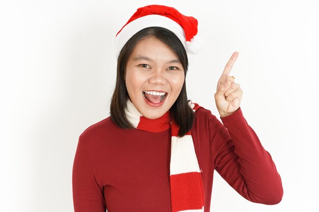 Lächeln und Aufzeigen einer schönen asiatischen Frau mit rotem Rollkragenpullover und Weihnachtsmütze