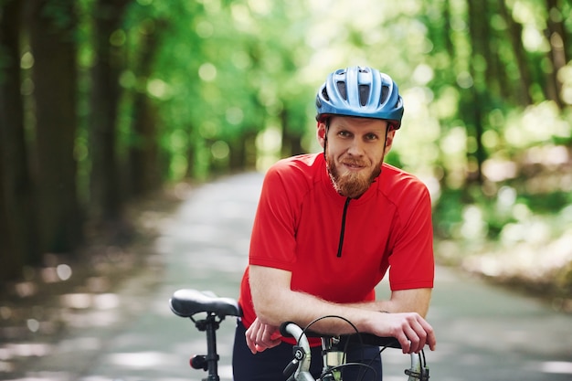Lächeln und entspannen. Radfahrer auf einem Fahrrad ist auf der Asphaltstraße im Wald am sonnigen Tag