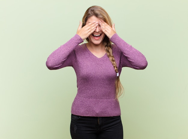 Foto lächeln und glücklich sein, die augen mit beiden händen bedecken und auf eine unglaubliche überraschung warten