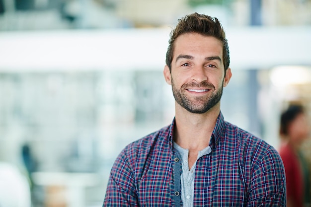 Lächelnd seinen Weg zum Erfolg Portrait eines glücklichen jungen Geschäftsmannes, der in seinem Büro steht