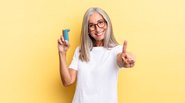 Lächelnd und freundlich aussehend, Nummer eins zeigend oder zuerst mit der Hand vorwärts, rückwärts zählend. Asthma-Konzept