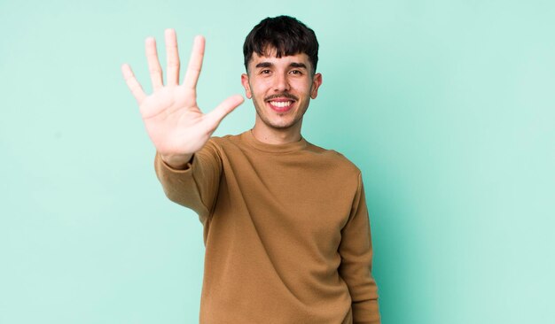 lächelnd und freundlich aussehend, Nummer fünf oder fünft mit der Hand nach vorne zählend