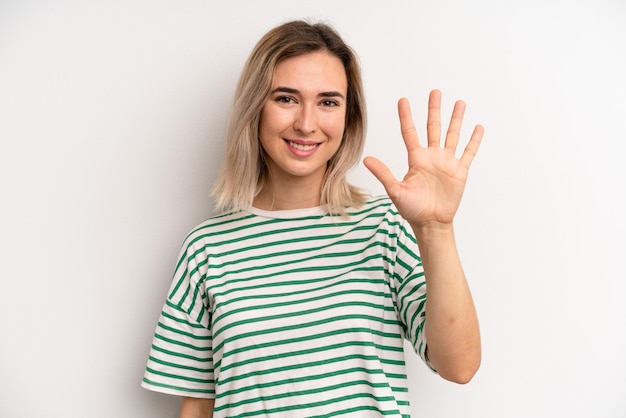 Foto lächelnd und freundlich aussehend, nummer fünf oder fünft mit der hand nach vorne zählend