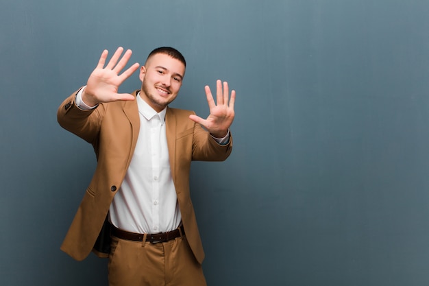 lächelnd und freundlich aussehend, Nummer zehn oder zehn mit der Hand nach vorne zeigend, Countdown