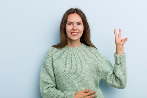 lächelnd und glücklich aussehen sorglos und positiv gestikulierend Sieg oder Frieden mit einer Hand