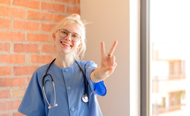 lächelnd und glücklich aussehend, unbeschwert und positiv, mit einer Hand Sieg oder Frieden gestikulieren