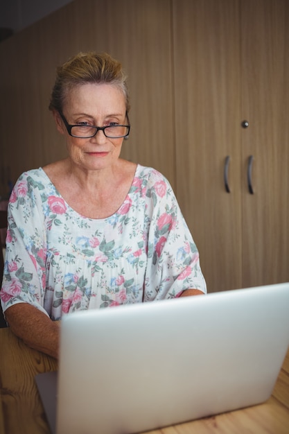 Lächelnde ältere Frau, die einen Laptop benutzt