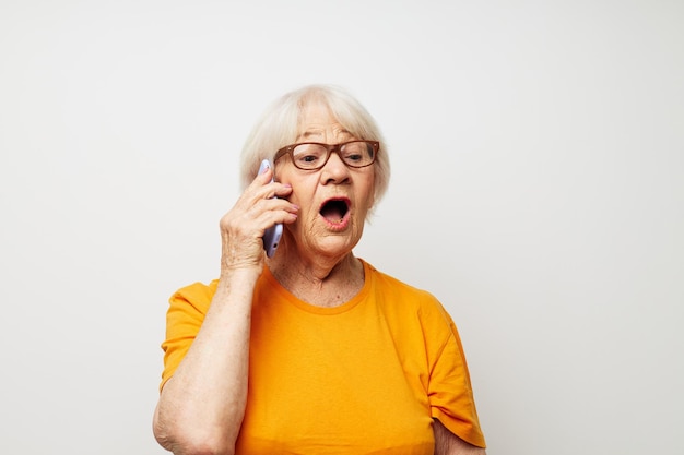 Lächelnde ältere Frau in modischer Brille mit einem Smartphone in der Hand, isolierter Hintergrund