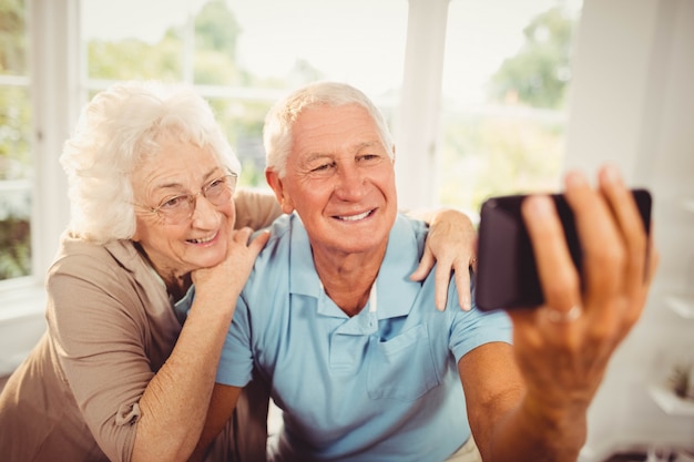 Lächelnde ältere paare, die zu hause selfie nehmen