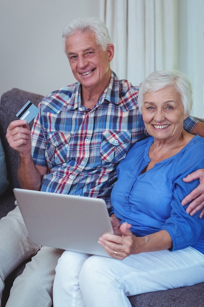 Lächelnde ältere Paare mit Kreditkarte und Laptop