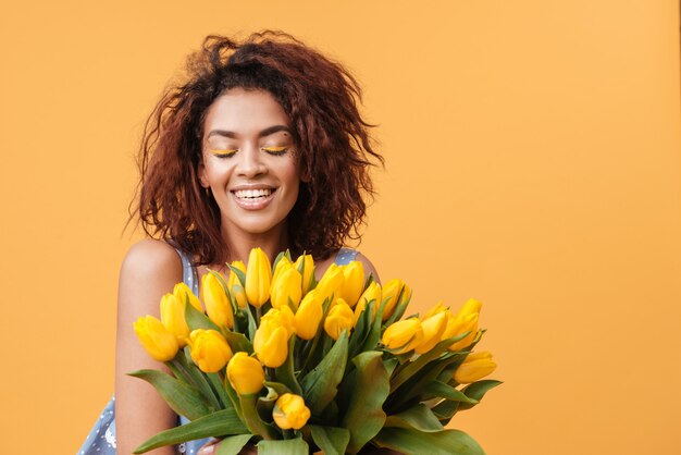 Lächelnde afrikanische Frau mit geschlossenen Augen, die Blumenstrauß halten