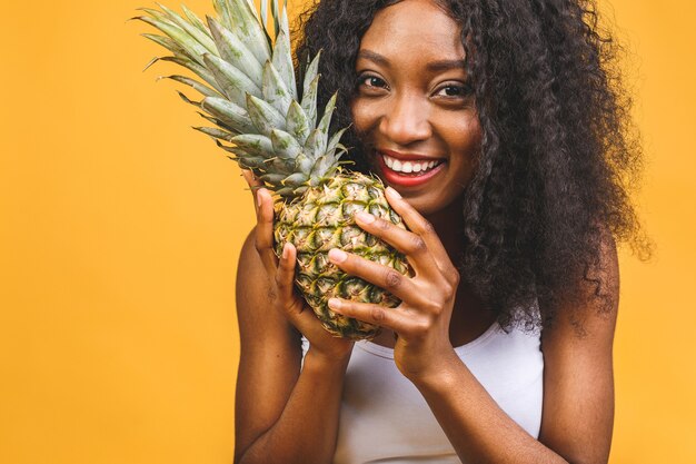 Lächelnde amerikanische afrikanische Frau, die eine Ananas hält