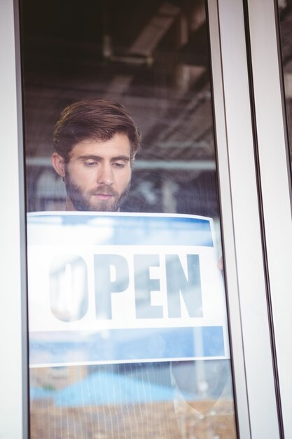 Lächelnde Arbeitskraft, die offenes Zeichen aufstellt