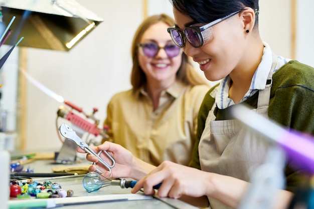 Lächelnde asiatische Frau, die mit Glas arbeitet