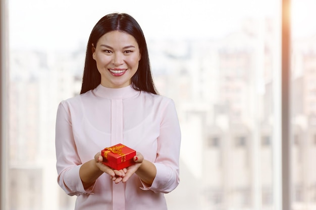 Lächelnde asiatische Frau, die rote Geschenkbox gibt