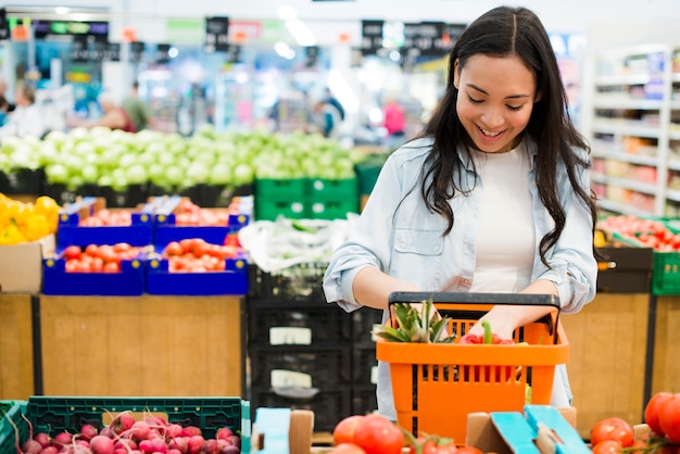 Lächelnde asiatische Frau, die Waren im Markt sortiert