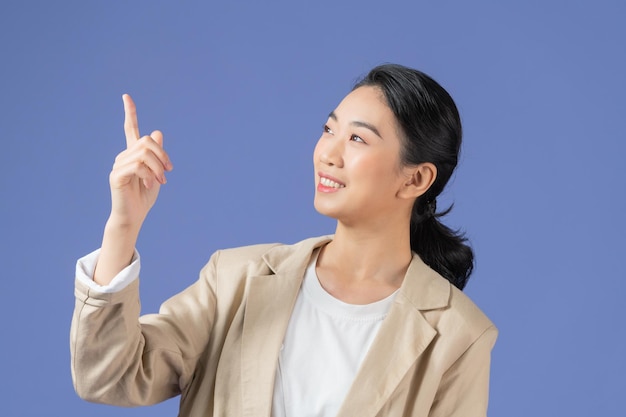 Lächelnde aufgeregte Frau, die Werbung zeigt, die mit dem Finger nach oben zeigt, stehend vor violettem Hintergrund