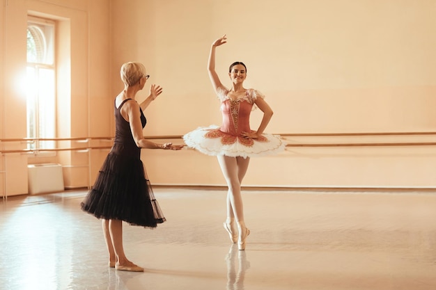 Lächelnde Ballerina, die mit ihrem Lehrer im Tanzstudio Ballettunterricht hat Kopieren Sie Platz