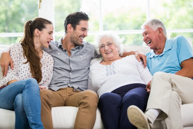 Lächelnde besprechende Familie beim Sitzen auf Sofa