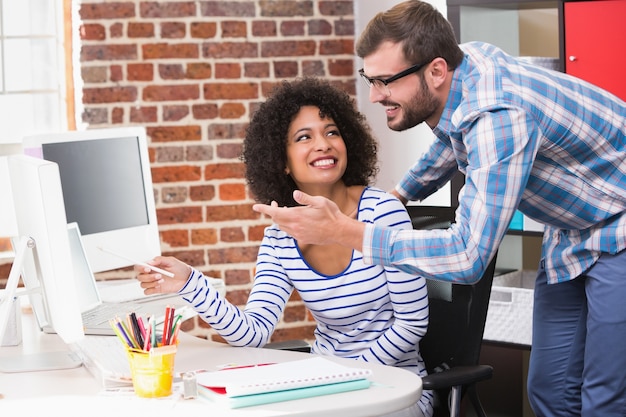 Lächelnde Bildeditoren, die Computer im Büro verwenden