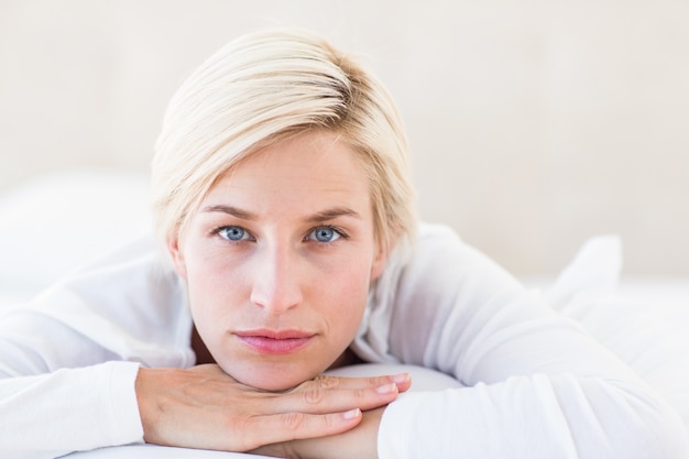 Foto lächelnde blondine, die auf dem bett liegen