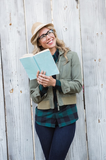 Lächelnde Blondine im Hut, der ein Buch hält