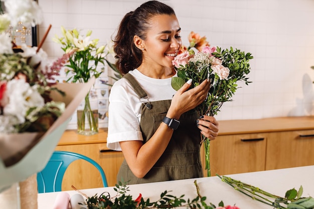 Lächelnde Blumenhändlerin hält einen Blumenstrauß im Laden