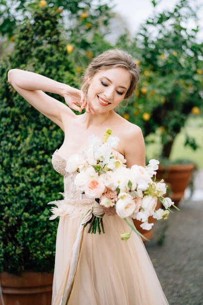 Lächelnde Braut in einem schönen Kleid mit einem Blumenstrauß