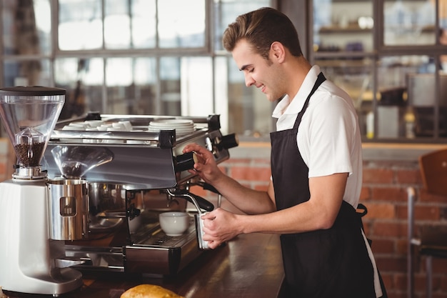 Lächelnde dämpfende Milch barista an der Kaffeemaschine