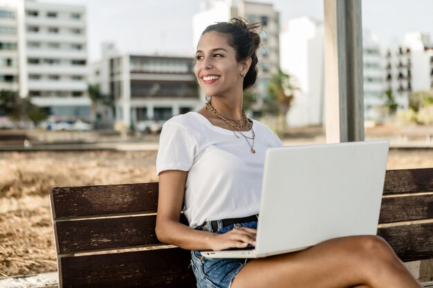 Lächelnde Dame mit dem Laptop, der weg schaut