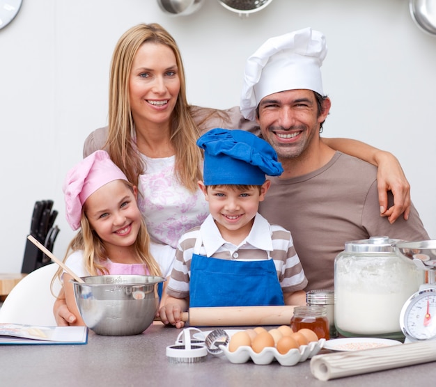 Lächelnde Eltern, welche die Kinder backen in der Küche helfen