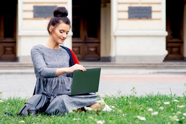 Lächelnde erwachsene Studentin benutzt Laptop im Freien.