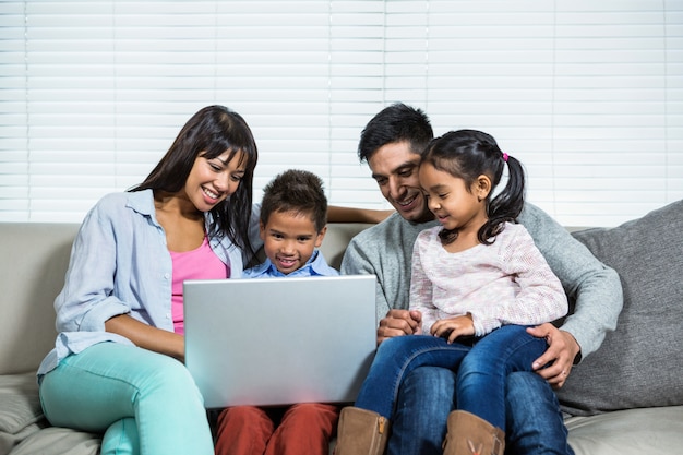 Lächelnde Familie auf dem Sofa unter Verwendung des Laptops