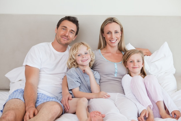 Lächelnde Familie, die auf dem Bett sitzt