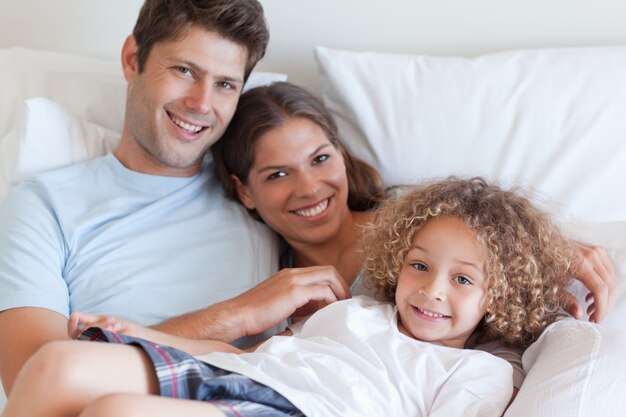 Lächelnde Familie, die auf einem Bett sich entspannt