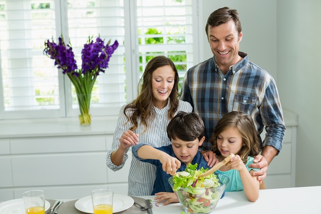 Lächelnde Familie, die Schüssel Salat in der Küche vorbereitet