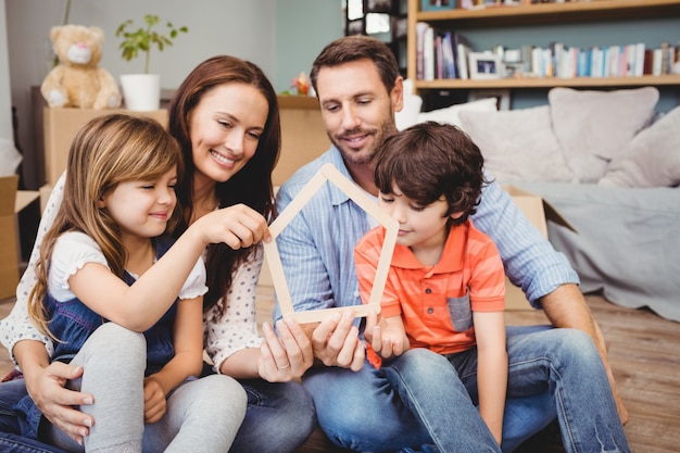 Lächelnde Familie, die zu Hause Hausform hält