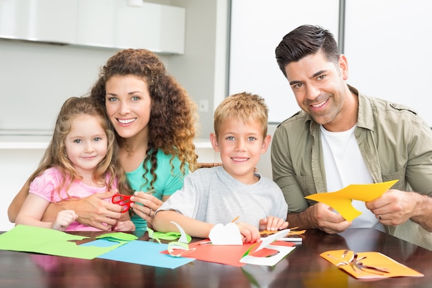 Lächelnde Familie, die zusammen Künste und Handwerk am Tisch tut