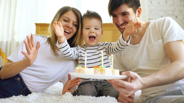 Lächelnde Familie feiert gemeinsam den Geburtstag ihres Sohnes, bevor sie Kerzen auf Kuchen bläst