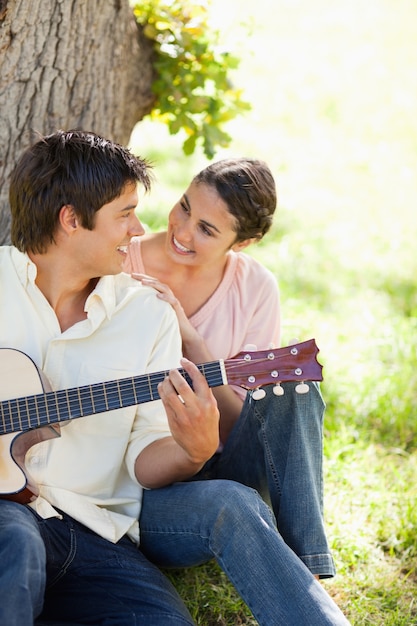 Lächelnde Frau beim Betrachten ihres Freunds, der eine Gitarre hält