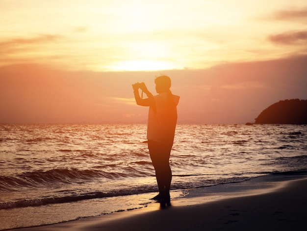 Lächelnde Frau des Schattenbildes, die Foto auf dem Strand macht.