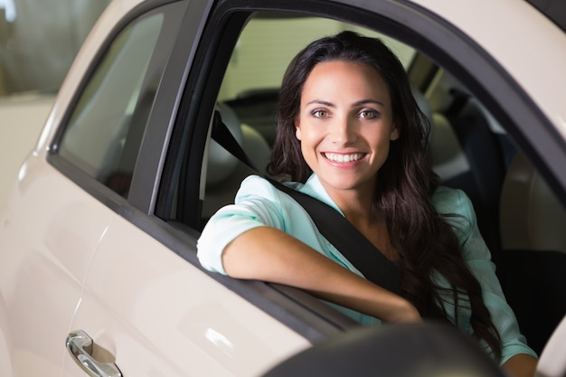 Lächelnde Frau, die am Steuer ihres neuen Autos sitzt