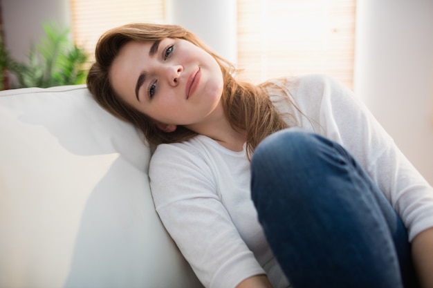 Lächelnde Frau, die auf der Couch im Wohnzimmer aufwirft