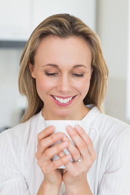 Lächelnde Frau, die Becher sitzt und hält