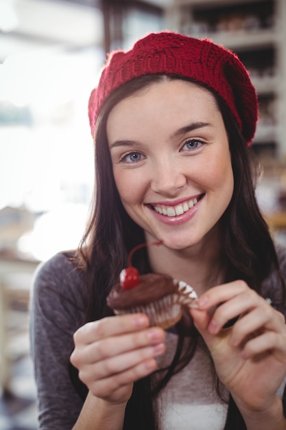 lächelnde Frau, die Cupcake hält