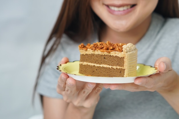 Lächelnde Frau, die den Kuchen betrachtet, den sie hielt