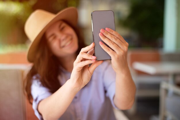 Lächelnde Frau, die draußen ein Selfie machtSonnenlicht im Hintergrund