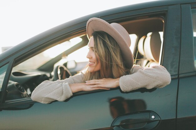 Lächelnde Frau, die durch das Fenster schaut, während sie im Auto sitzt